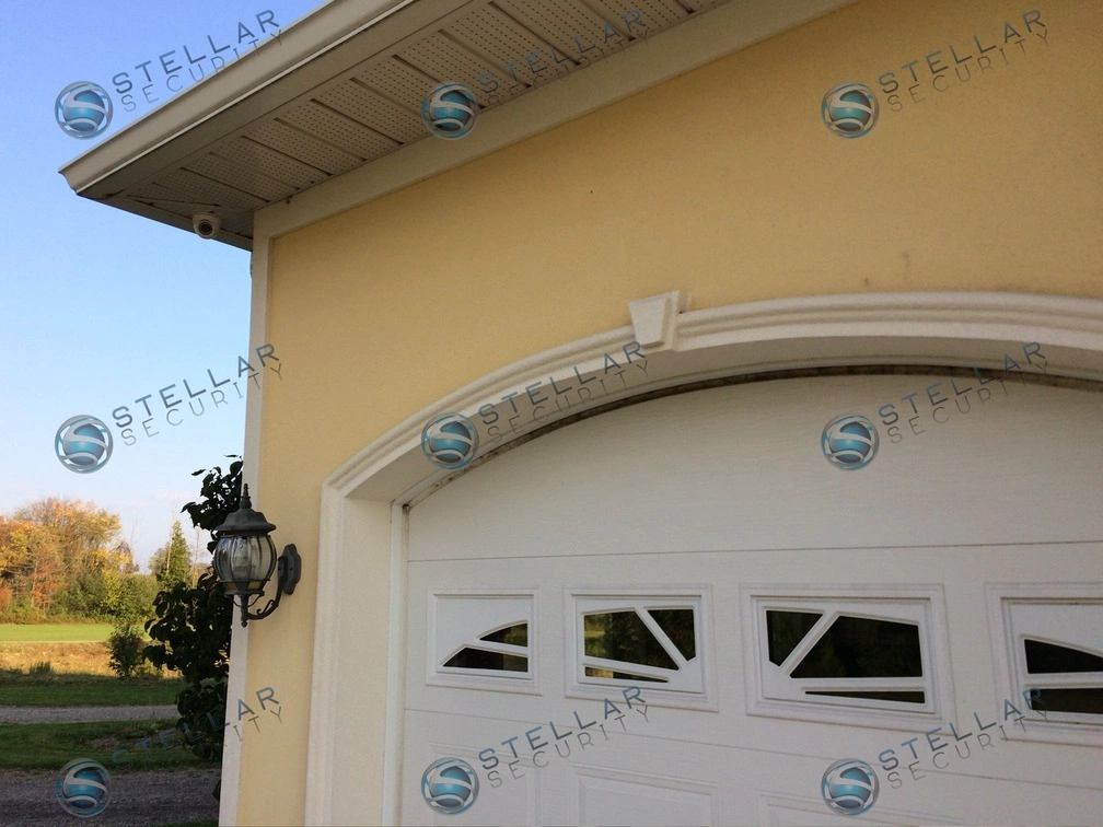 Soffit security camera installed above white arch garage door of a Cambridge residence