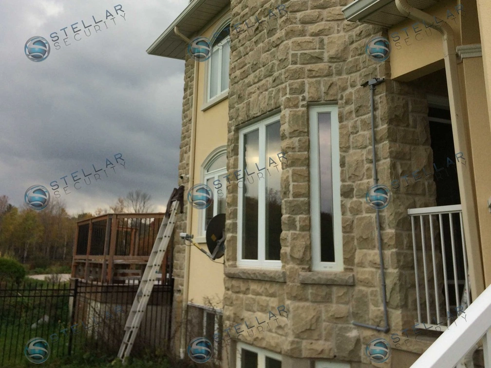Exterior security camera mounted on soffit along stone and stucco wall of a Cambridge home