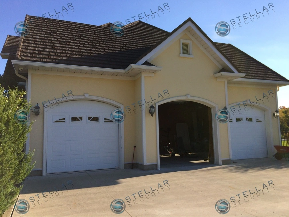 Full view of triple garage exterior on yellow stucco Cambridge home with security camera placement