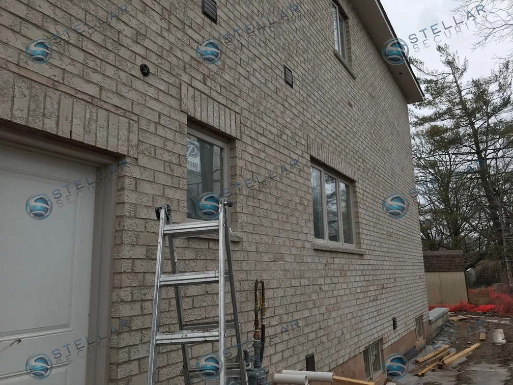 Security camera mounted on side brick wall covering walkway during Mississauga home build