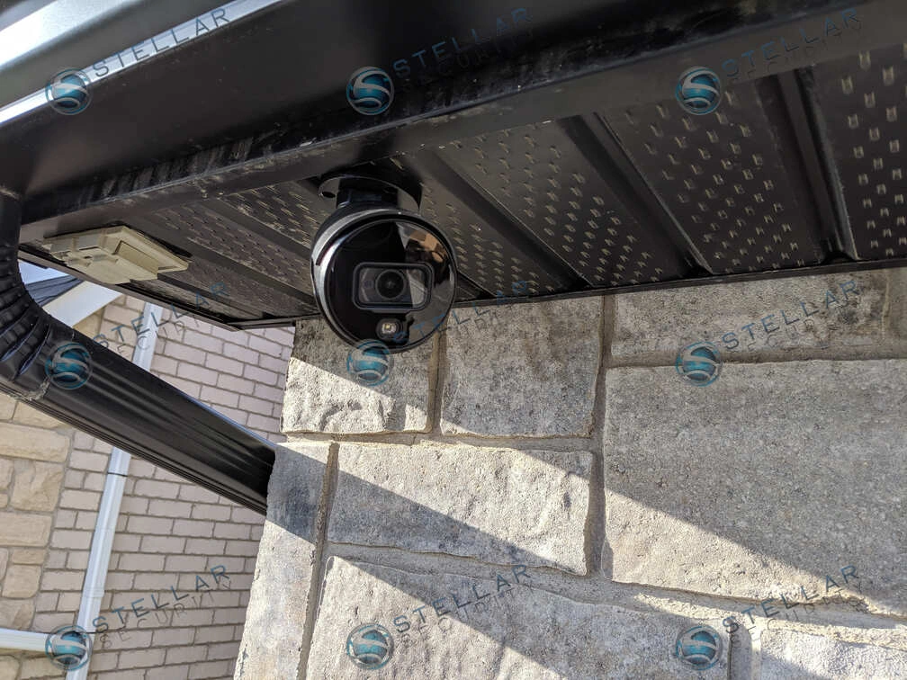Close-up of a black 4K turret security camera soffit-mounted on a Toronto home