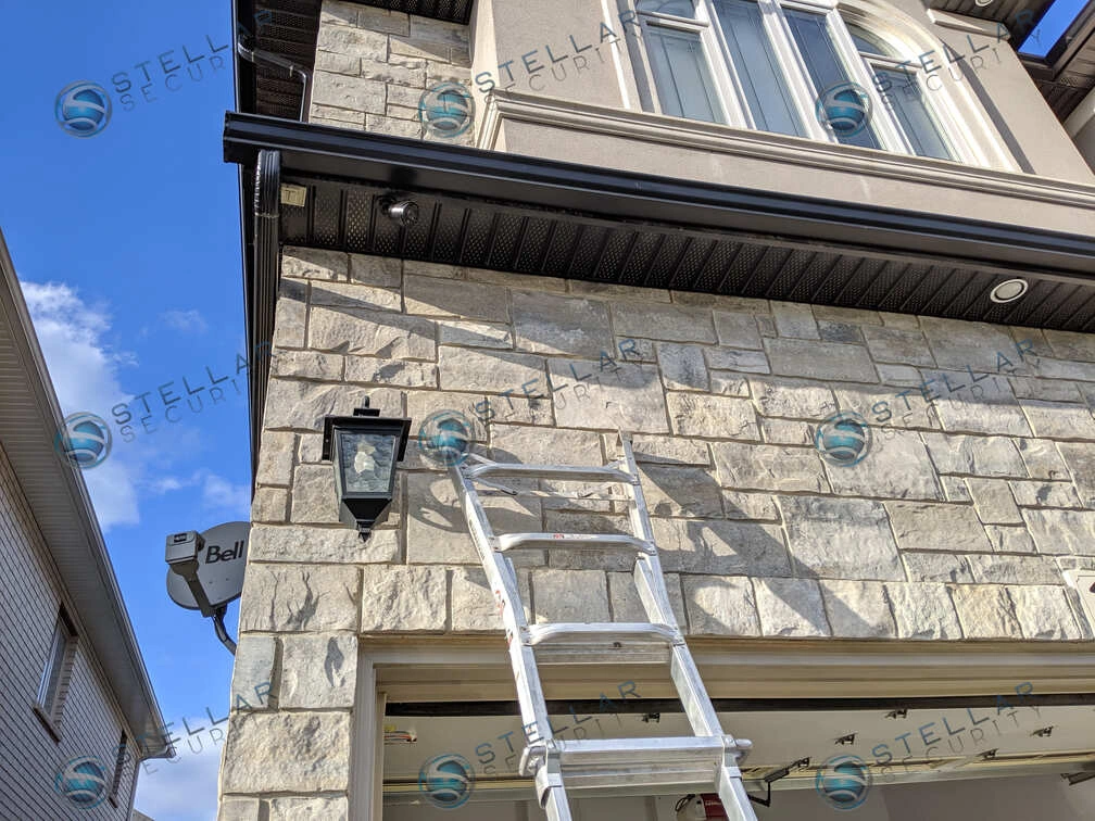 Outdoor security camera installed above garage door with stone exterior in Toronto
