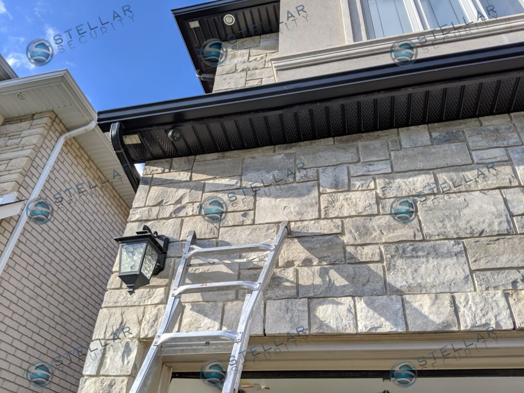 Dark 4K dome security camera mounted on black soffit trim above a Toronto garage