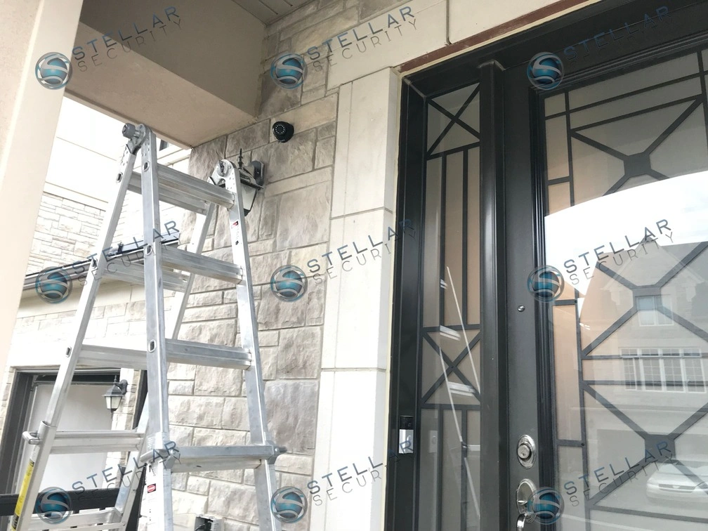 Black outdoor security camera mounted near front door entry trim of a Vaughan residential property