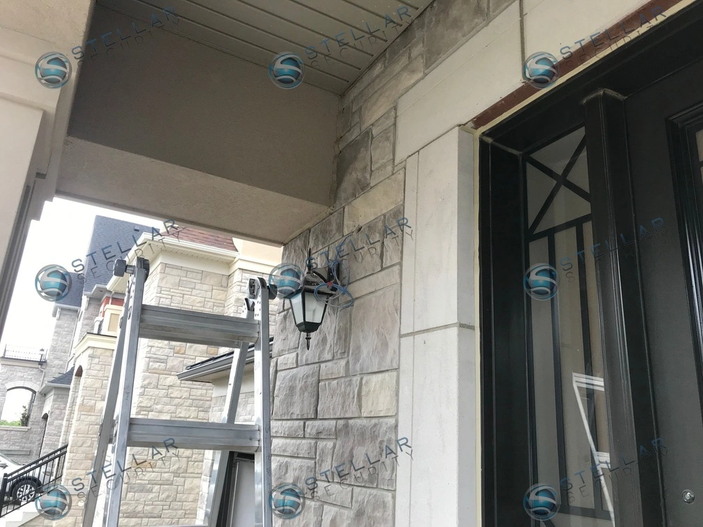 Security camera installation underway above front entrance porch of a Vaughan stone home