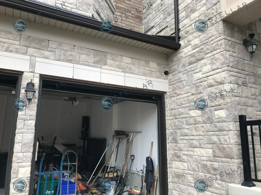Dark 4K security camera mounted on stone wall above garage entrance of a Vaughan residence