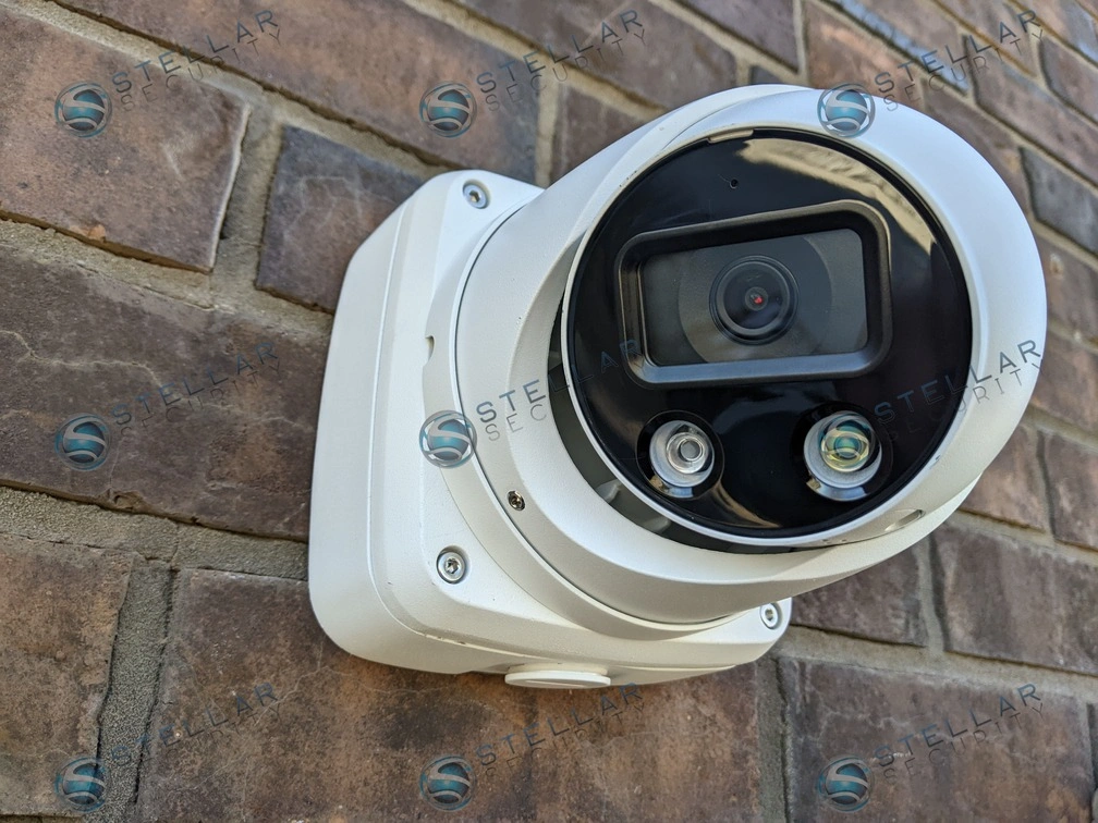Close-up of a 4K white outdoor turret security camera mounted on exterior brick masonry.