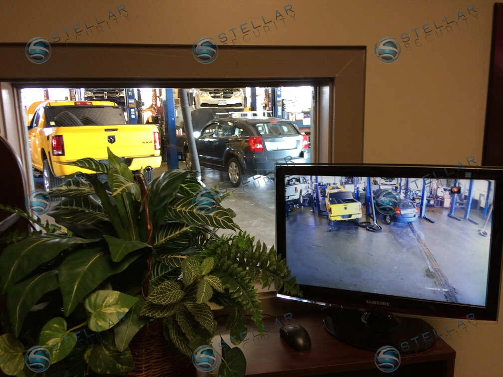 Security camera monitor screen displayed near service bay entrance in a car dealership