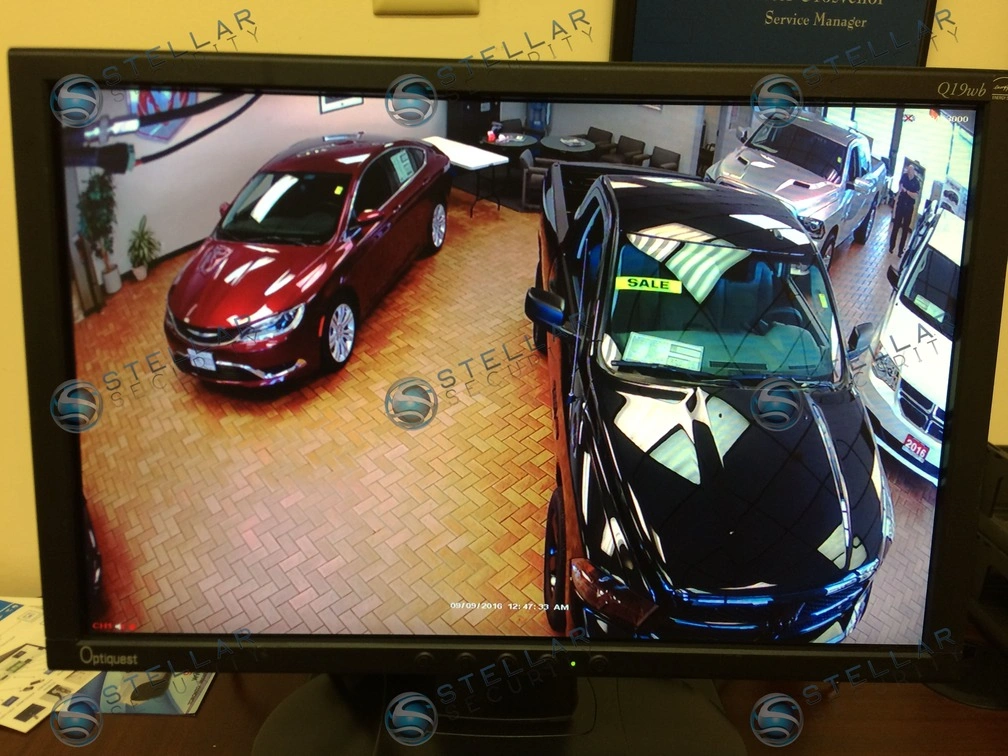 Live CCTV video surveillance feed displaying luxury vehicles on a dealership showroom floor