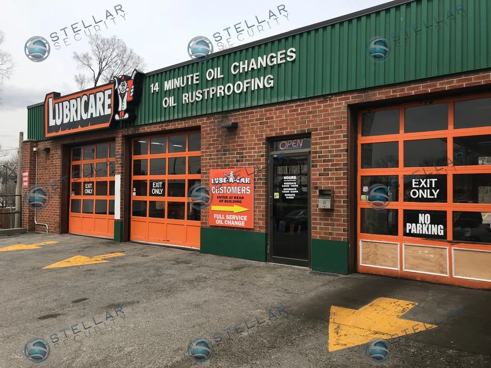 Exterior view of auto repair shop garage doors, brick facade, and customer entrance with security camera coverage