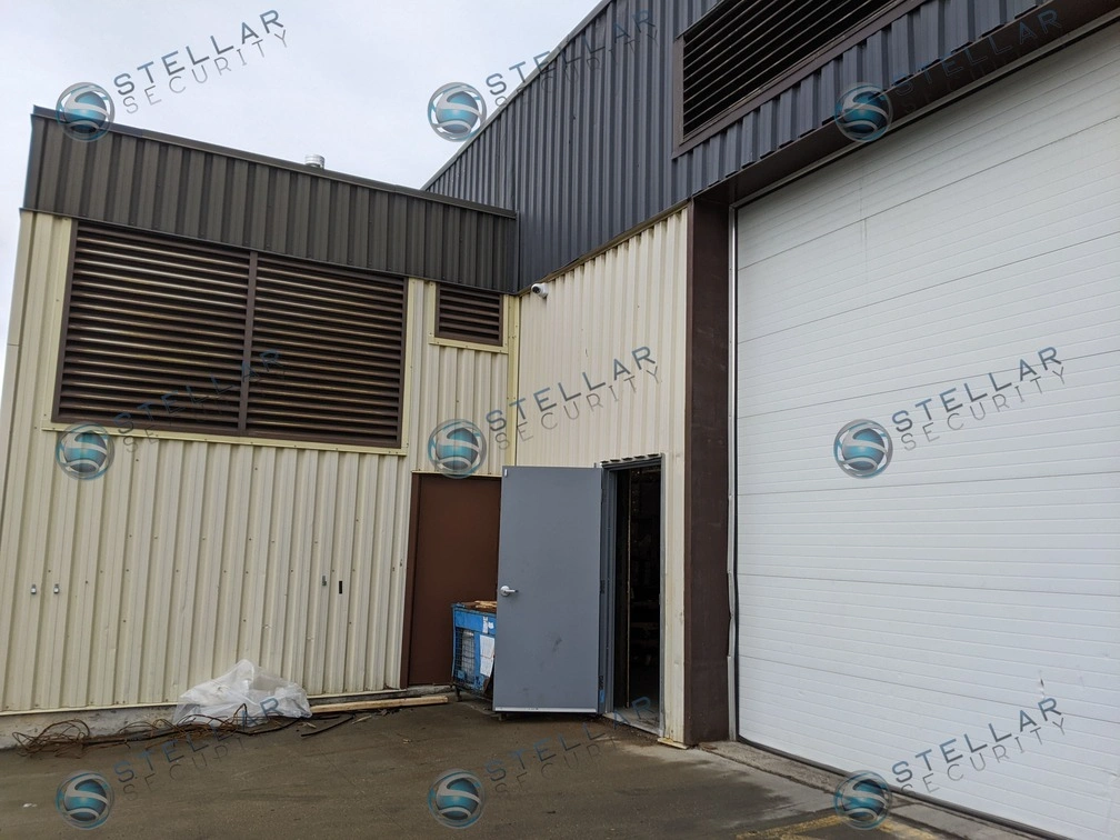 Wide exterior view of warehouse loading dock doors monitored by perimeter security cameras.
