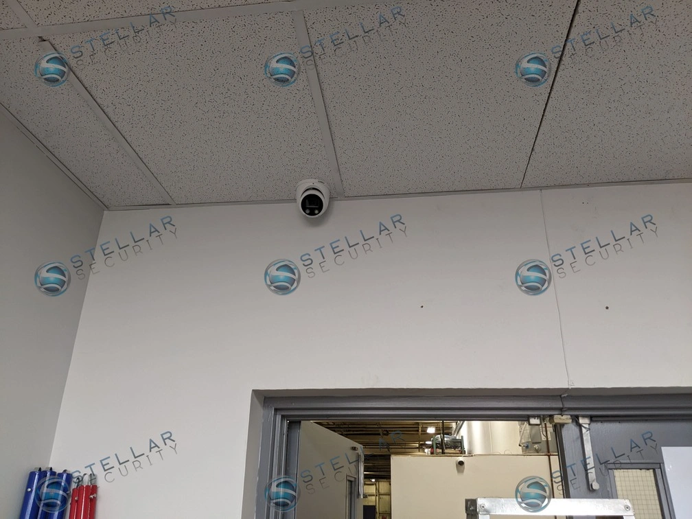 Compact dome security camera neatly integrated into a commercial office tile ceiling.