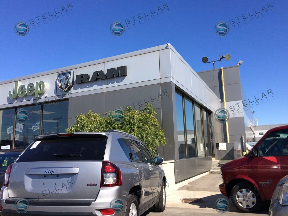 Outdoor commercial security camera installed on dealership front facade overlooking main entrance