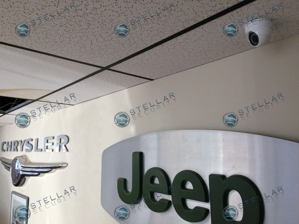 Overhead dome security camera monitoring dealership main showroom floor and wall display