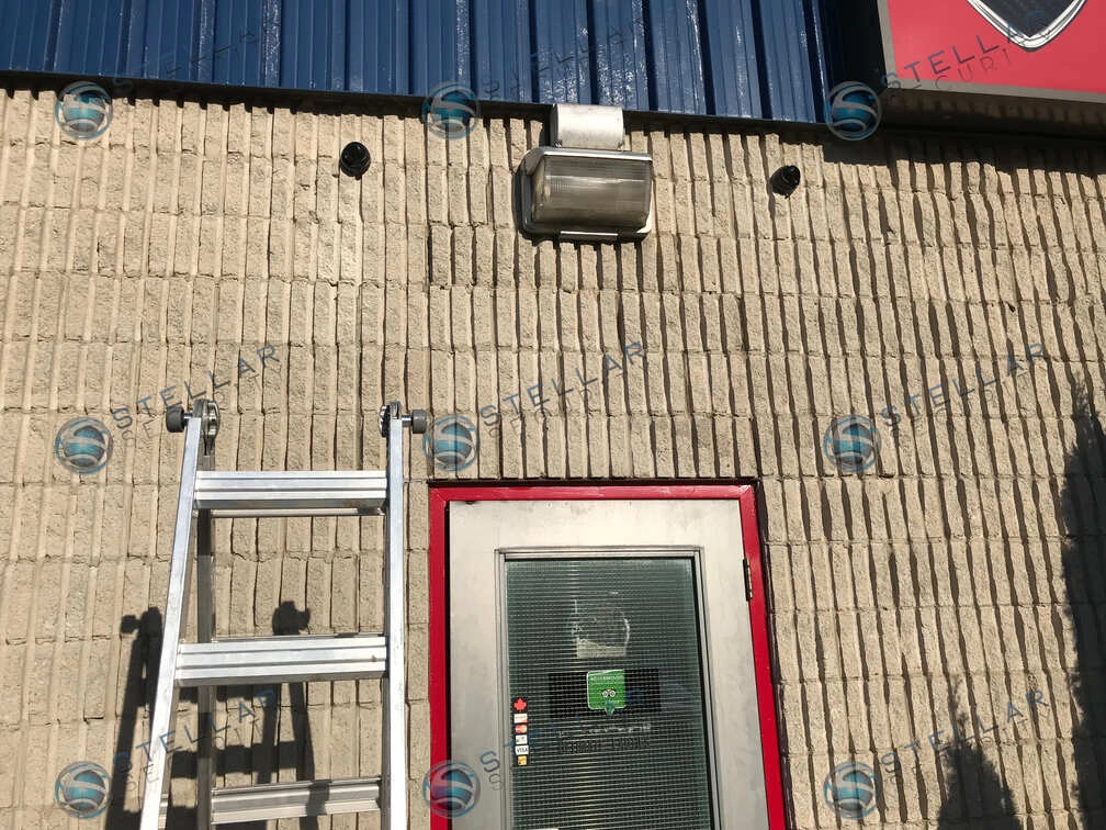 Monitor feed showing high-angle indoor security camera coverage of exotic sports cars parked inside service bay.