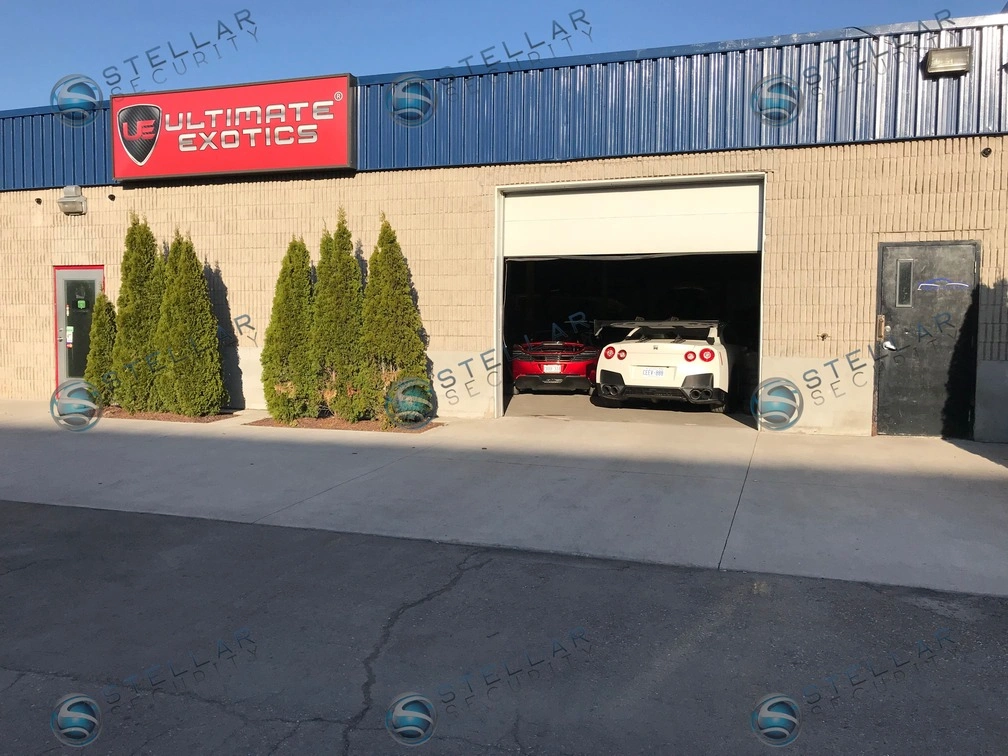 Exterior building facade of auto shop featuring open garage bay and security cameras.