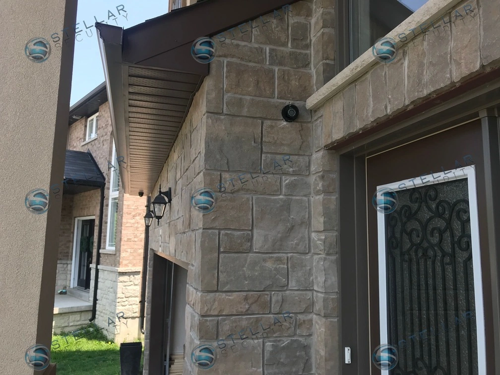 Security camera mounted on stone facade protecting main front entry doors of a Hamilton home
