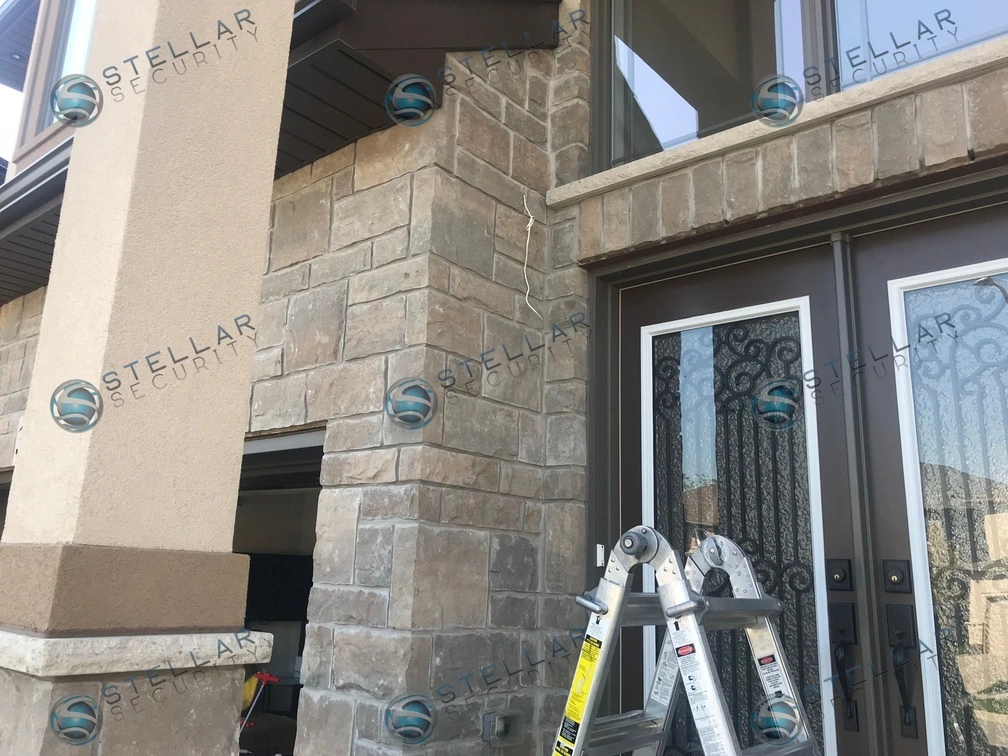 Security camera installation near front entrance doors on stone masonry of a Hamilton home