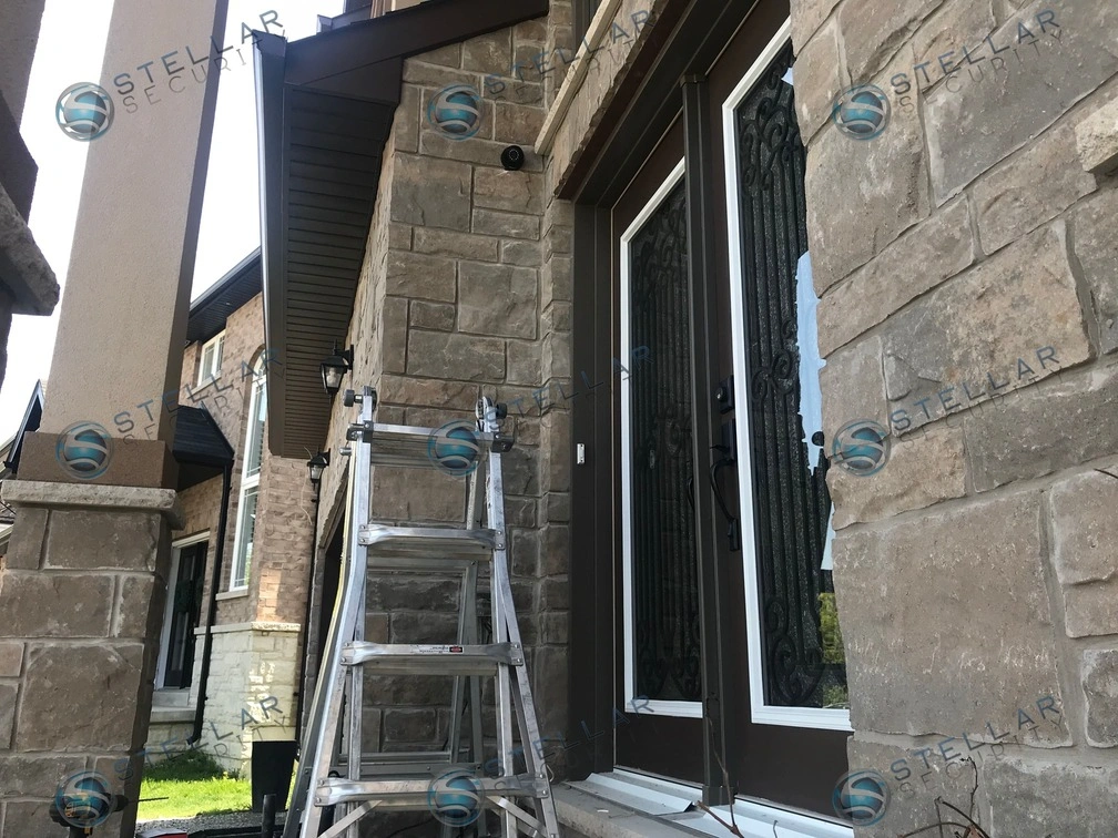 Dark security camera mounted on dark soffit trim near front porch entrance in Hamilton