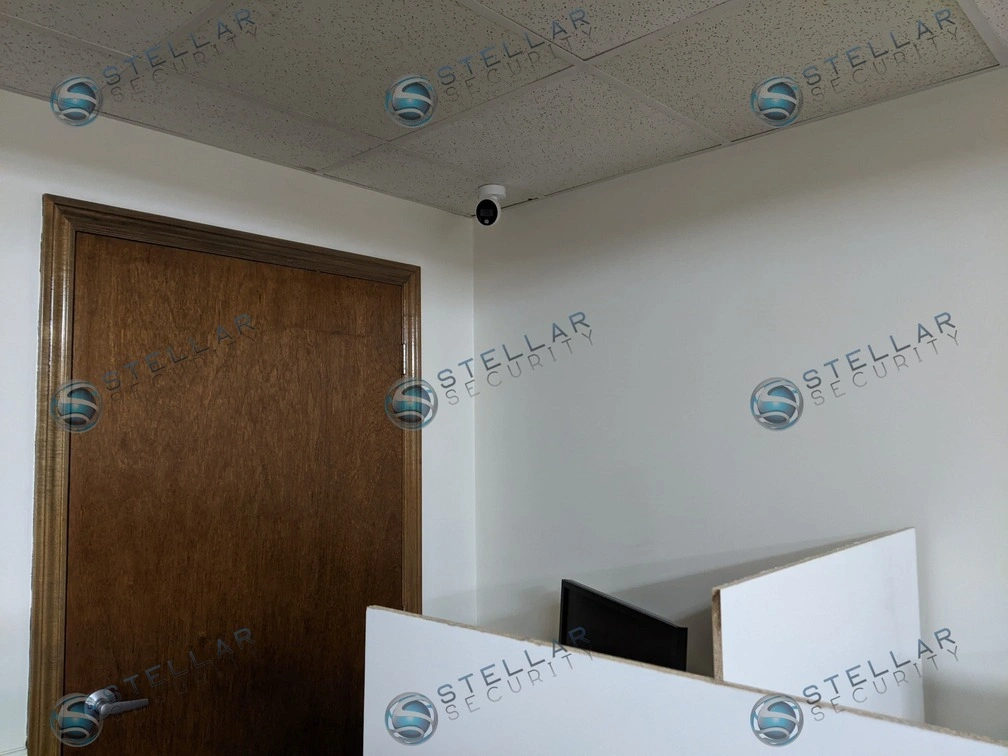 Compact dome security camera installed in the ceiling corner of a school classroom.