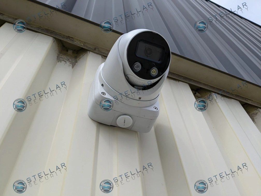 Close-up of a white commercial turret camera installed on industrial metal wall panels.