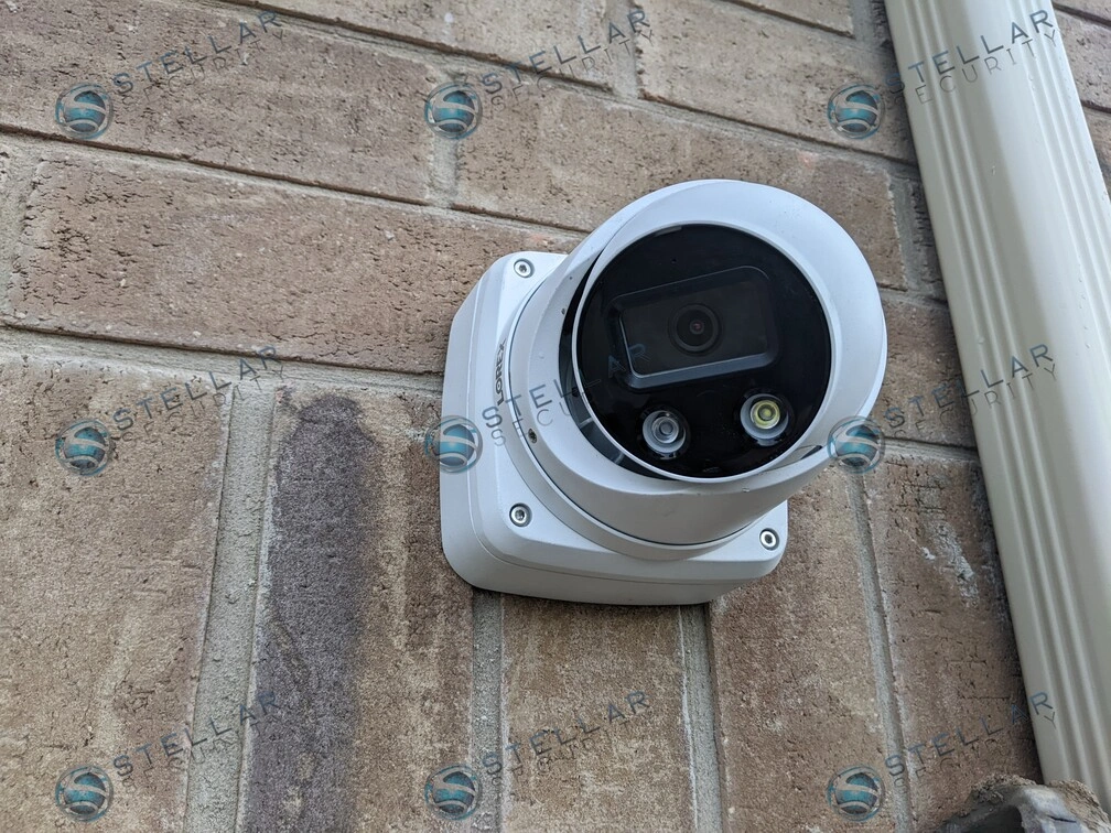 Side angle close-up of white 4K security camera with junction box on brick wall in Kitchener