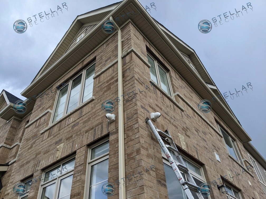 Security camera installed on upper brick wall corner near roof soffit in Kitchener