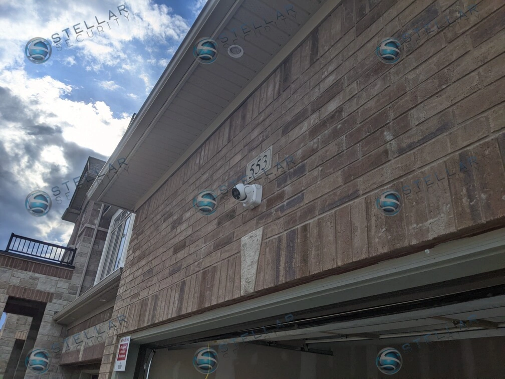 Low angle view of outdoor security camera mounted on brick wall above garage soffit in Kitchener