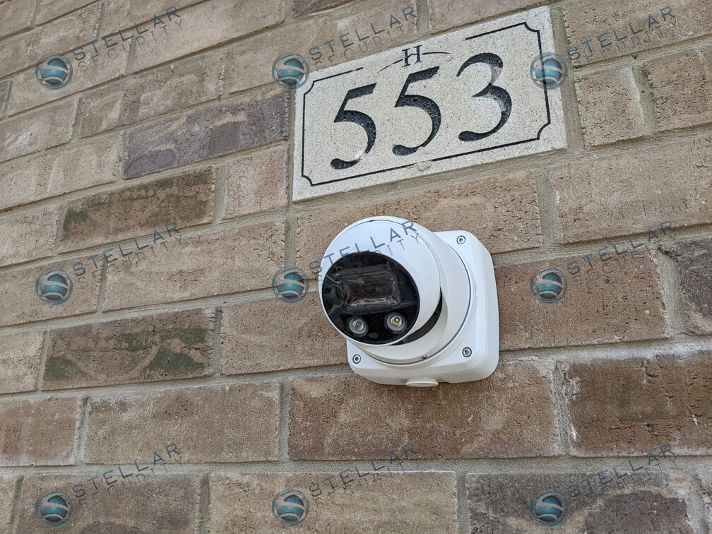 White turret security camera installed directly below address plate on brick facade in Kitchener