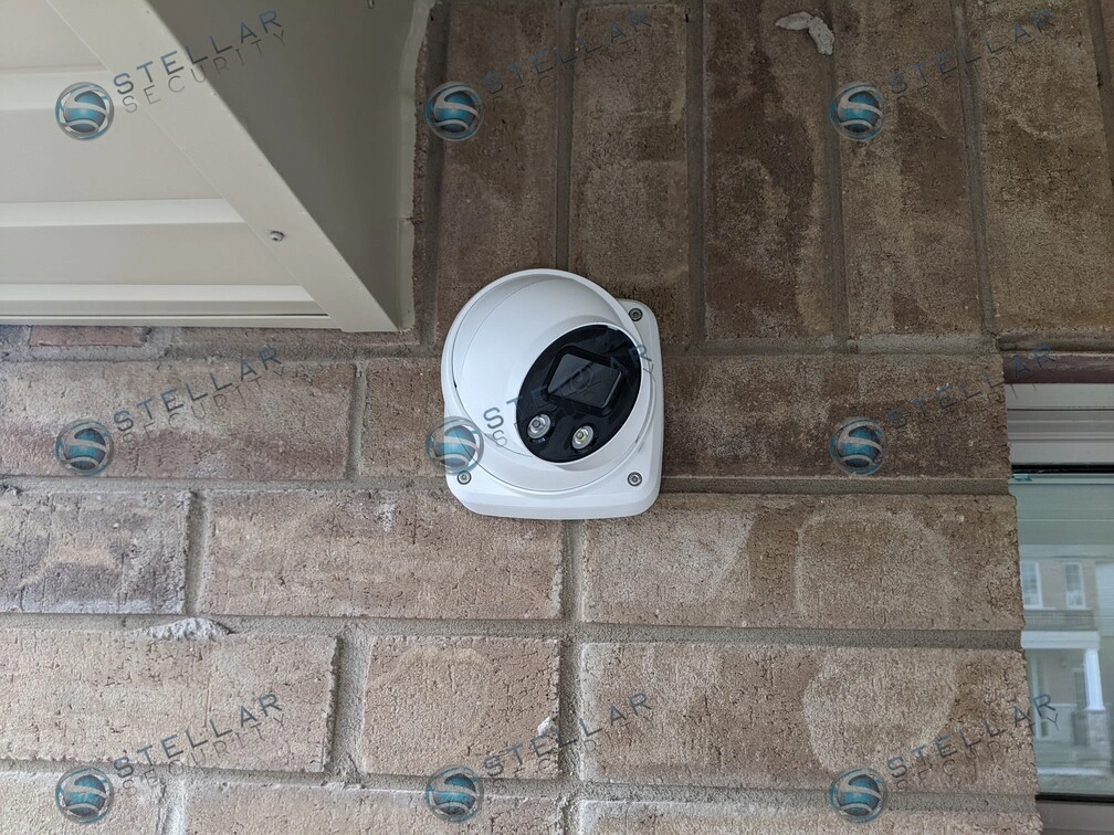 White 4K turret security camera mounted flush against exterior brick wall in Kitchener