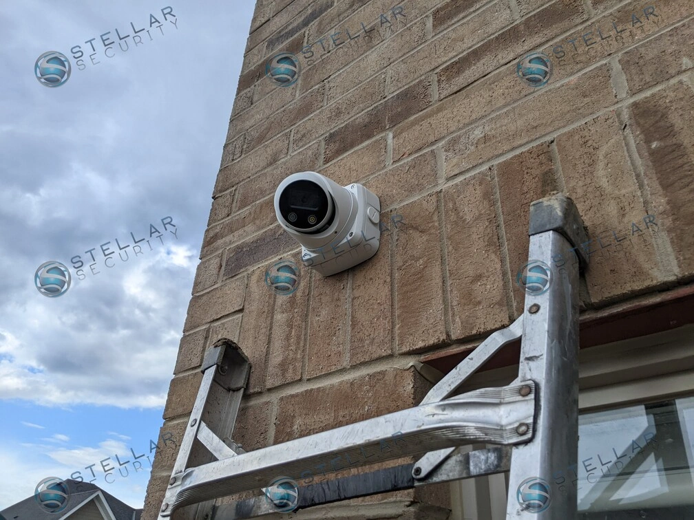 White turret security camera mounted high on stone brick exterior corner in Kitchener
