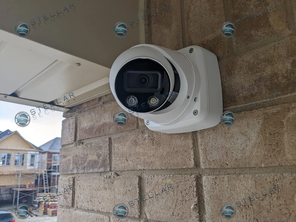 Close-up of white outdoor turret security camera mounted on brick wall near soffit in Kitchener