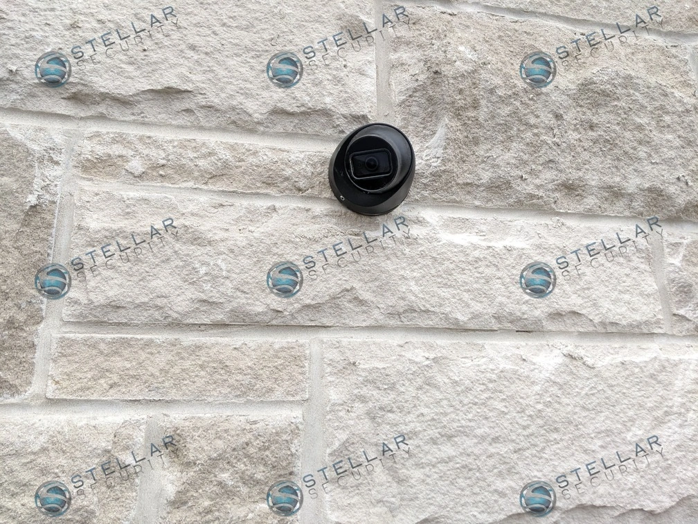 Detailed shot of a black 4K security camera mounted directly onto light stone masonry in London