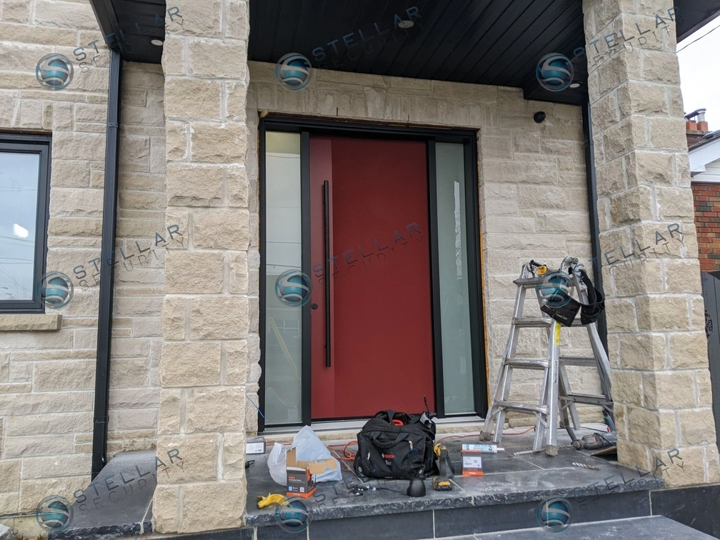Front entrance porch with dark security camera mounted on light stone near a red front door in London
