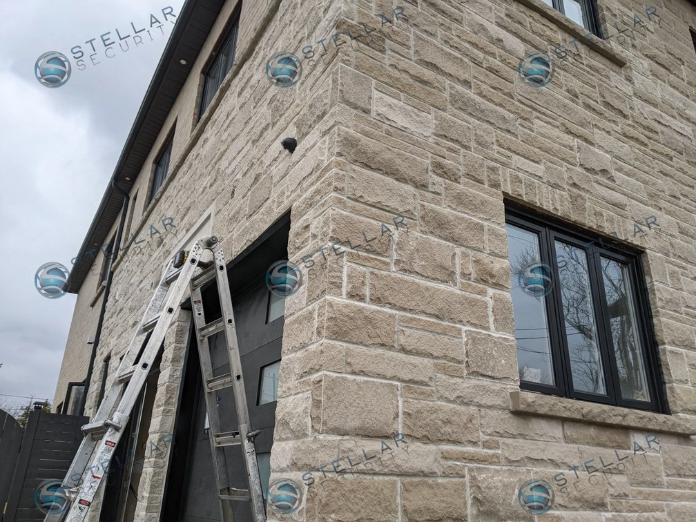 Security camera mounted high on stone corner wall monitoring garage and driveway in London