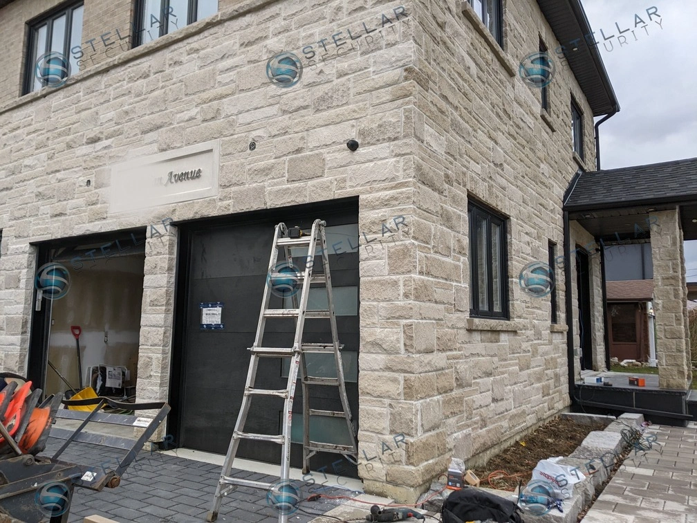 Wide front exterior view of custom stone home showing comprehensive security camera placement in London