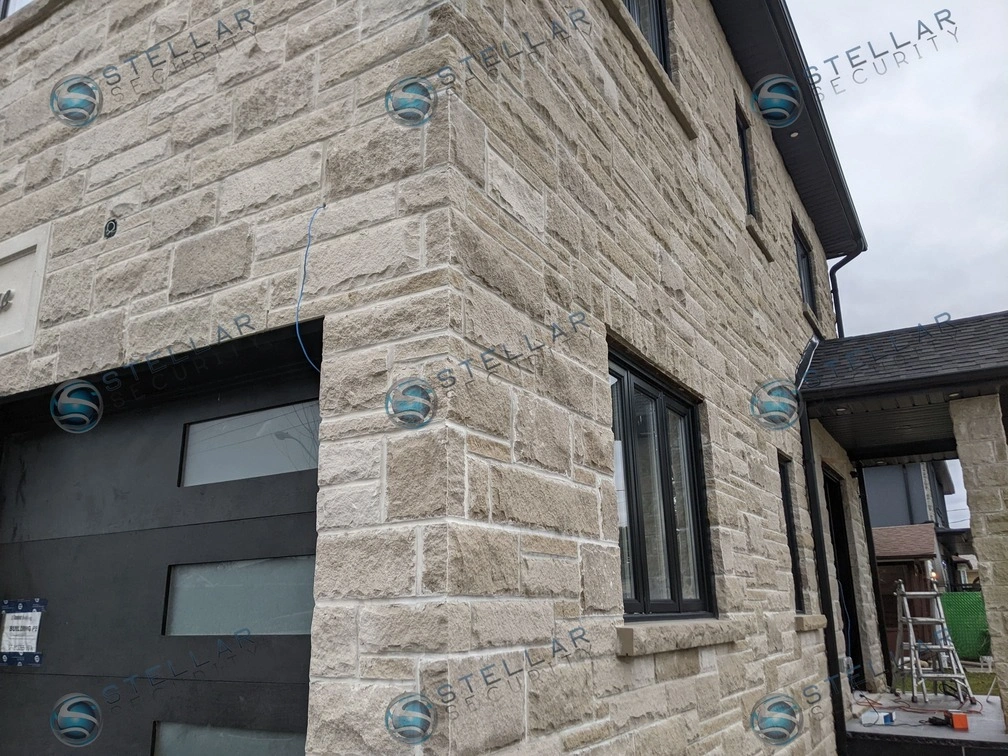 Side angle view of stone exterior home showing outdoor security camera coverage above garage in London