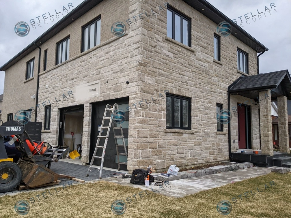 Security camera installation above modern dark garage door on a stone home in London