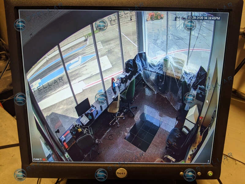 High-angle security camera monitor feed displaying control tower office layout and workstations.