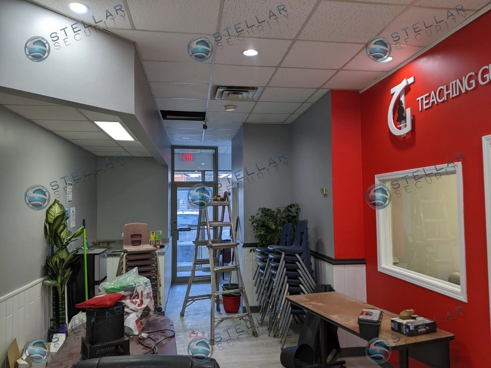 Wide view of a school entrance hallway and reception counter monitored by ceiling security cameras.