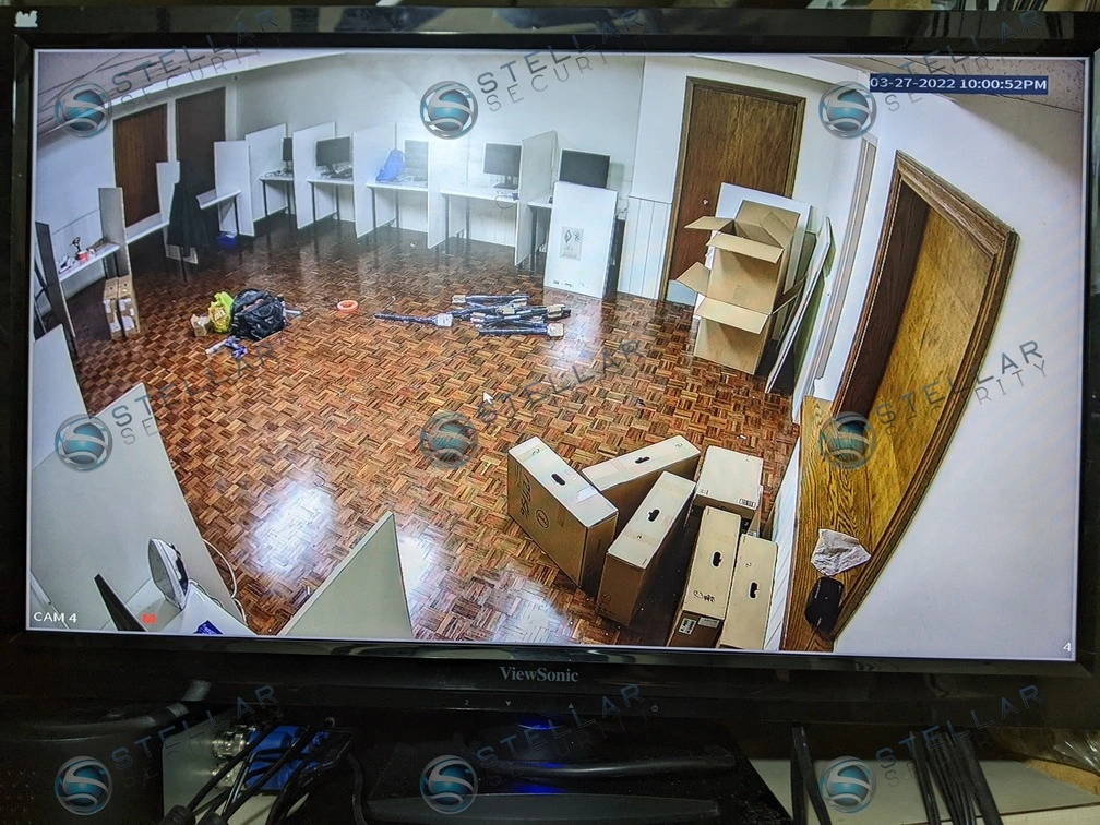 Monitor screen displaying real-time wide-angle security camera feed of a computer lab classroom.