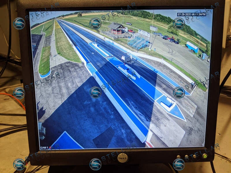 Live CCTV monitor view showing full length of drag strip racing track from control tower camera.
